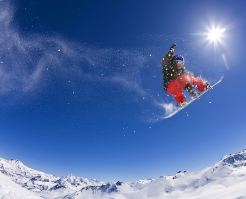 Snowboarder jumping across snowy mountain